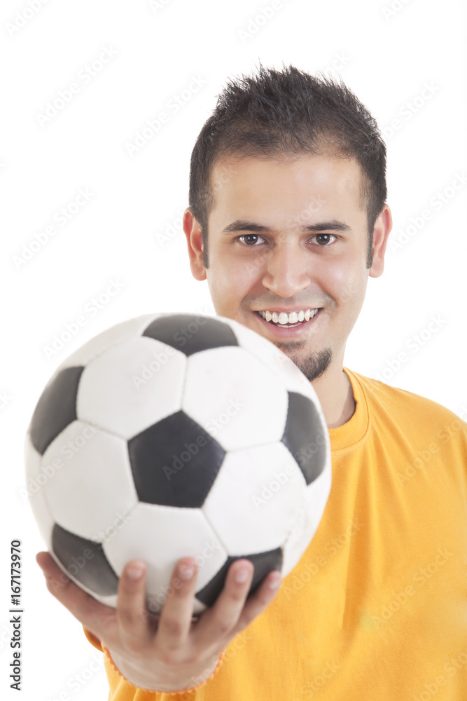 Portrait of young man smiling while holding soccer ball over white background Portrait of young man smiling while holding soccer ball over white background