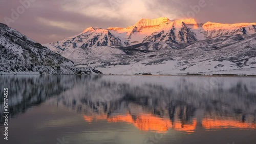 Sun lighting up snow covered mountain reflecting over Deer Creek Reservoir Utah. photo