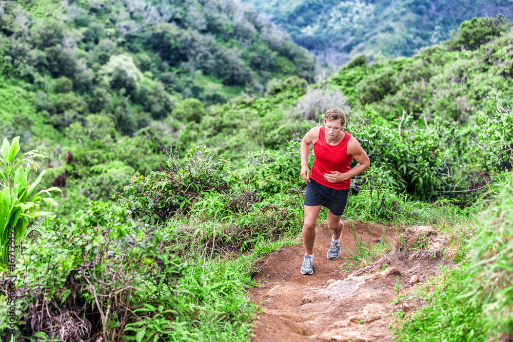 Trail running man runner going up in mountain forest. Ultra running race marathon in Hawaii.