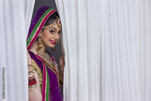 Portrait of beautiful Indian bride smiling amidst curtains