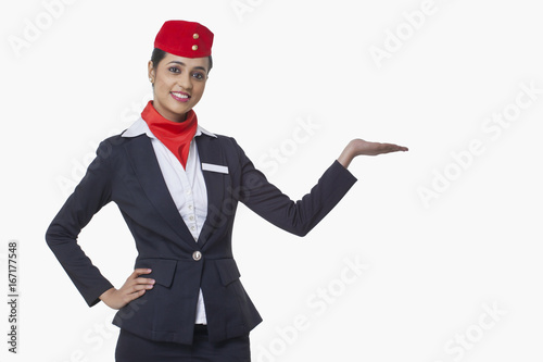 Portrait of young airhostess holding invisible product isolated over white background  photo