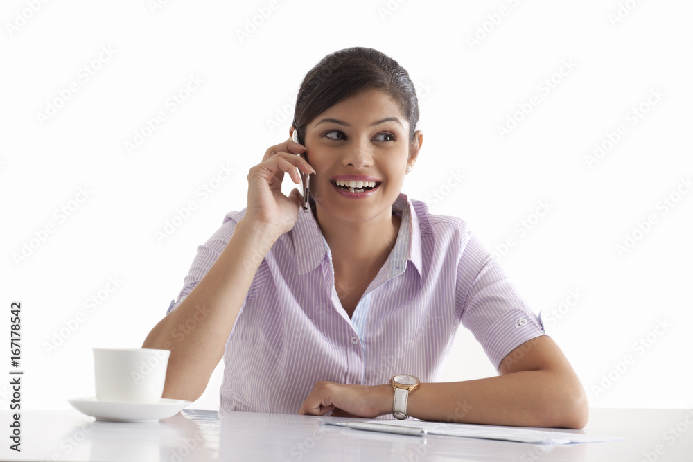 Smiling young businesswoman using cell phone at her desk Smiling young businesswoman using cell phone at her desk