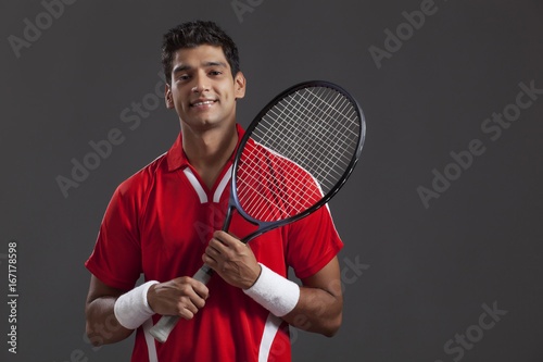 Confident young man with tennis racket over black background © IndiaPix