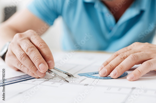 Male hands holding a pair of compasses and a protractor