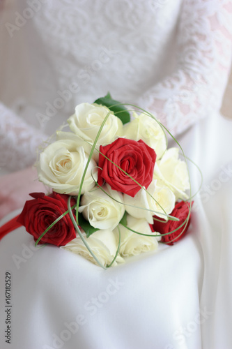 Bride in white wedding dress sitting and holding wedding bouquet