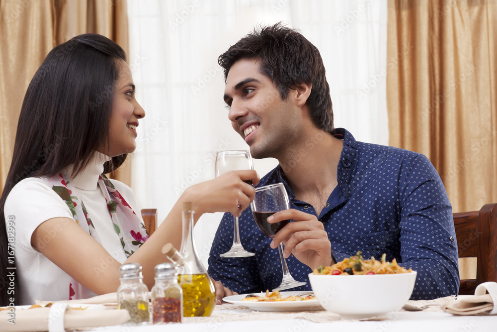 Couple looking at each other while clinking wine glass at restaurant Couple looking at each other while clinking wine glass at restaurant