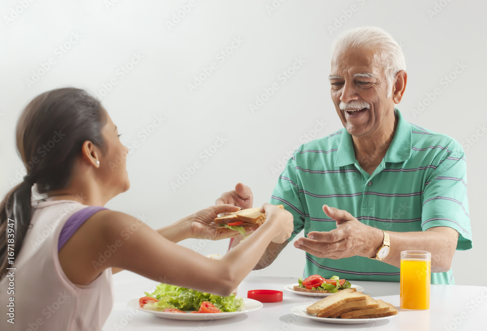 Grandfather and granddaughter eating breakfast