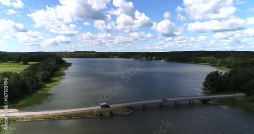 Cars on island road, Cinema 4k aerial view of cars driving over a bridge and on a asphalt road in the countryside on a island, on a finnish lake, on a sunny day, in Lohjansaari, lohja, Finland photo