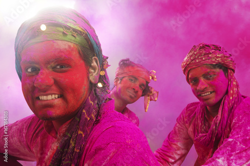 Young Indian Men sitting on floor, covered in colored powder during holi color festival
