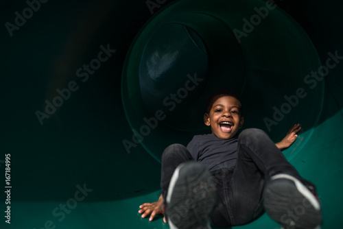 Boy laughing while playing on slide