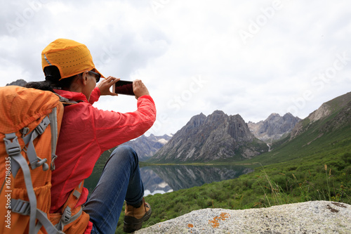 young woman taking photo with smartphone outdoors