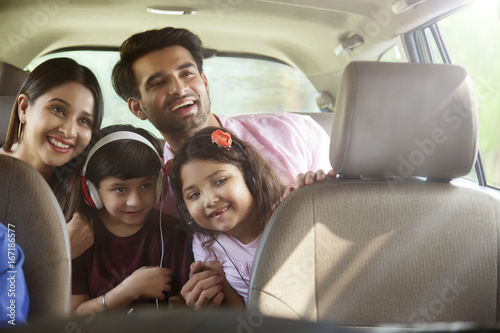 Happy family sitting in back seat looking out of car window 