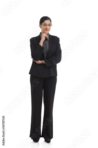 Full length portrait of confident businesswoman with hand on chin against white background 
