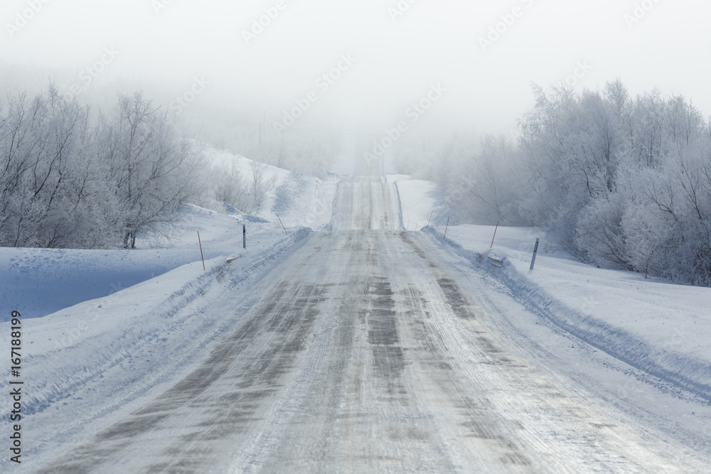 Obraz premium Remote frozen road in fog in winter
