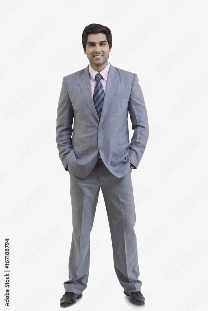 Full length portrait of happy young businessman with hands in pockets standing against white background Full length portrait of happy young businessman with hands in pockets standing against white background