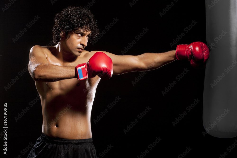 Handsome young man hitting punching bag Handsome young man hitting punching bag