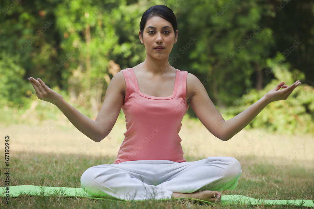 Portrait of woman in lawn sitting in lotus position Portrait of woman in lawn sitting in lotus position