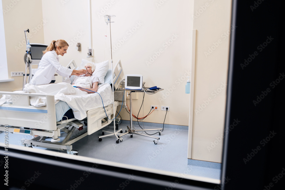 Dedicated wise capable woman checking on her elderly patient Dedicated wise capable woman checking on her elderly patient