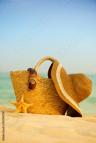 Bag of hat and glasses on the beach.
