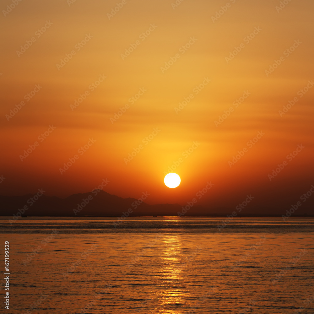 orange sunset at the sea with mountains silhouettes on horizont