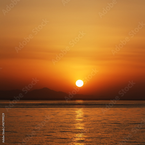 orange sunset at the sea with mountains silhouettes on horizont
