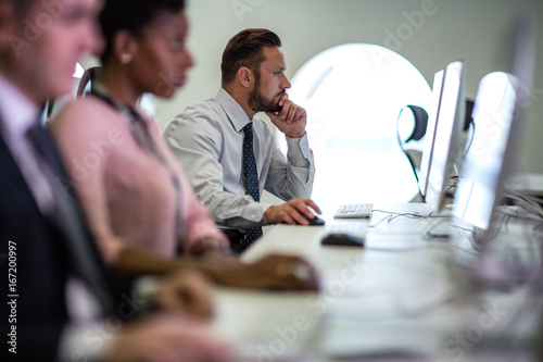 Businessman using computer in crowded office photo