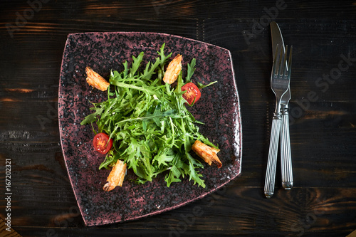 Salad with shrimps and arugula serve on a table with wine photo