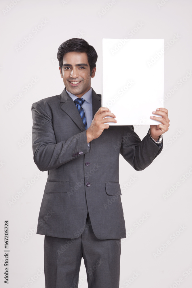 Portrait of businessman holding empty placard over gray background Portrait of businessman holding empty placard over gray background