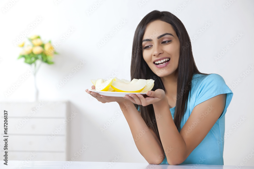 Young woman holding plate with slices of melon at home Young woman holding plate with slices of melon at home