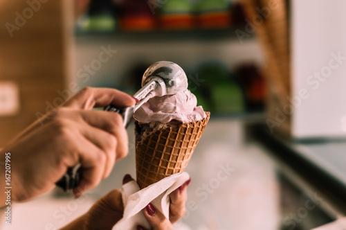 Fototapeta Putting ice cream to cone, summer concept