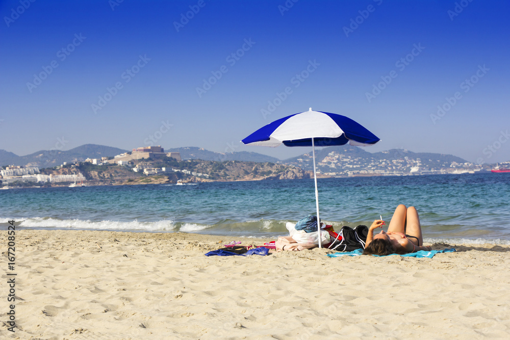Ibiza sandy beach young girl under a umbrella