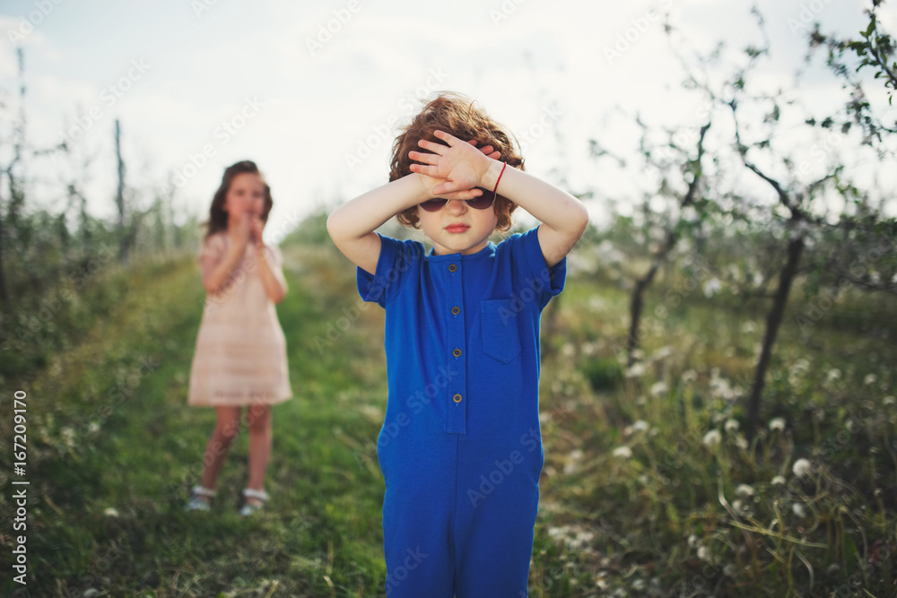Naklejka premium little boy and girl in blooming garden