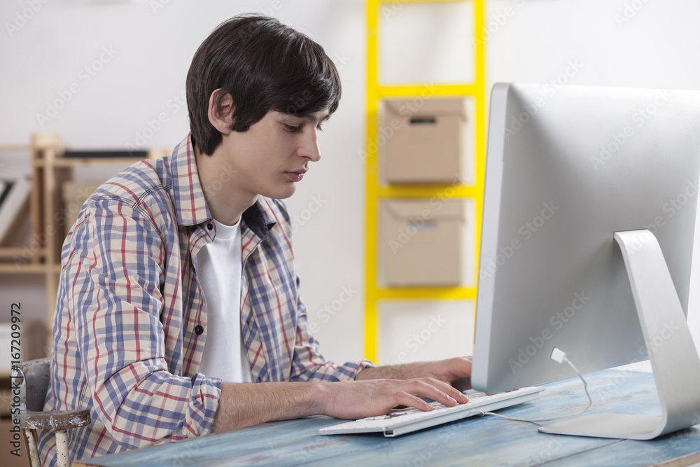 Teenager at the desk is programing and doing homework for the school Teenager at the desk is programing and doing homework for the school
