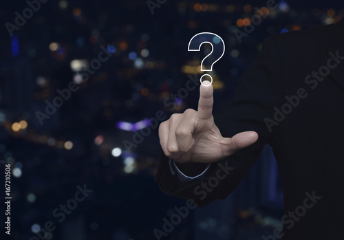 Businessman pressing question mark sign icon over blur colorful night light city tower, Customer support concept