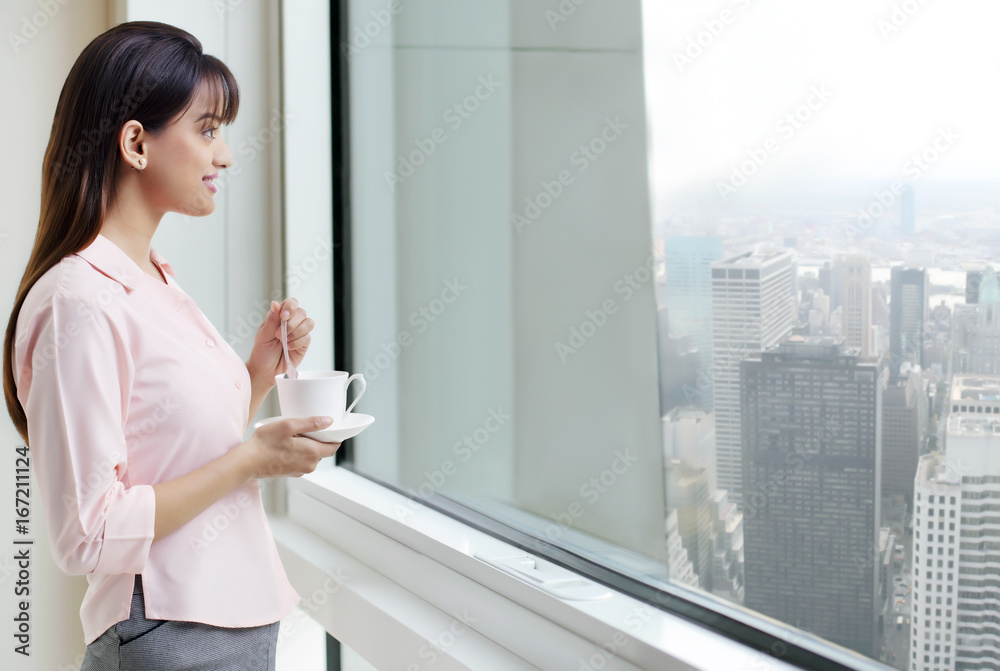Woman with coffee staring out a window 