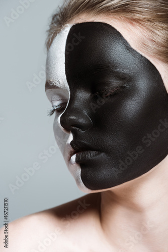 young beautiful girl with creative white and black bodyart on face  isolated on grey