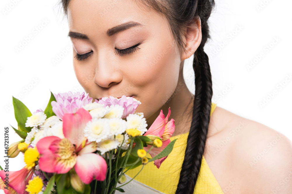 beautiful asian girl with closed eyes smelling flowers isolated on white