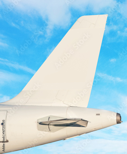 Plane tail fin - sky with white clouds in background