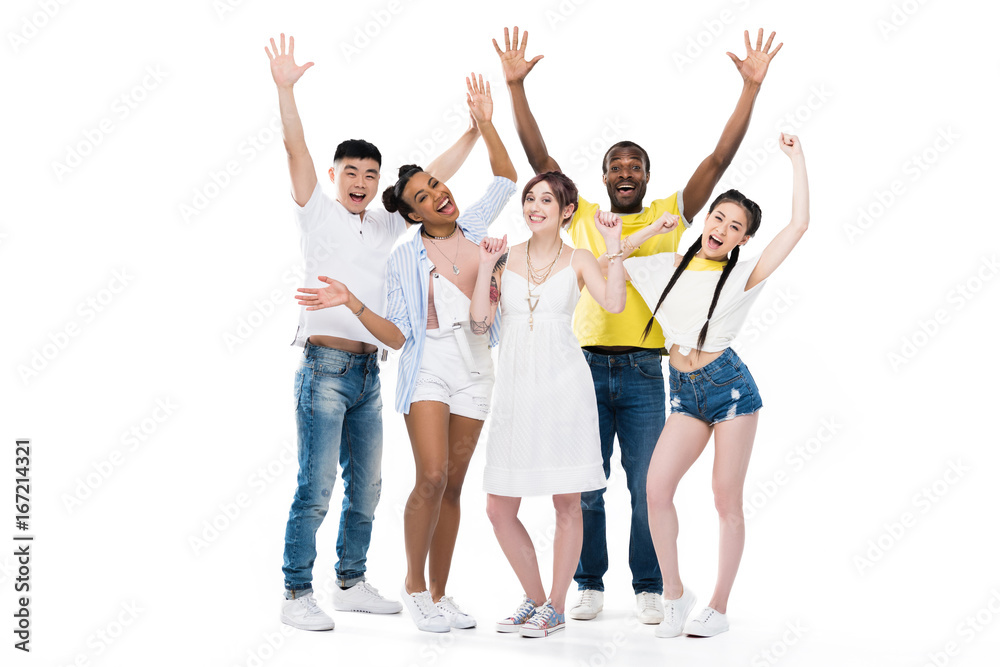 happy young multiethnic people raising hands and smiling at camera isolated on white