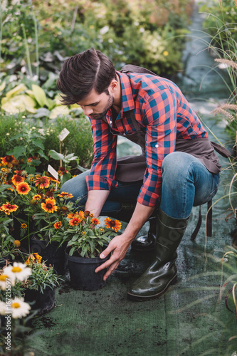 young caucasian gardener in rubber boots working with flowers in garden © LIGHTFIELD STUDIOS
