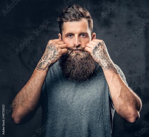 A man touches his moustache over grey background. photo