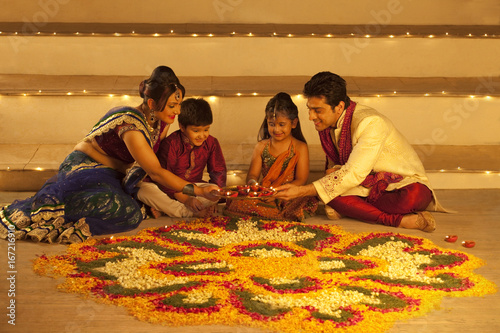 Family arranging diyas on rangoli