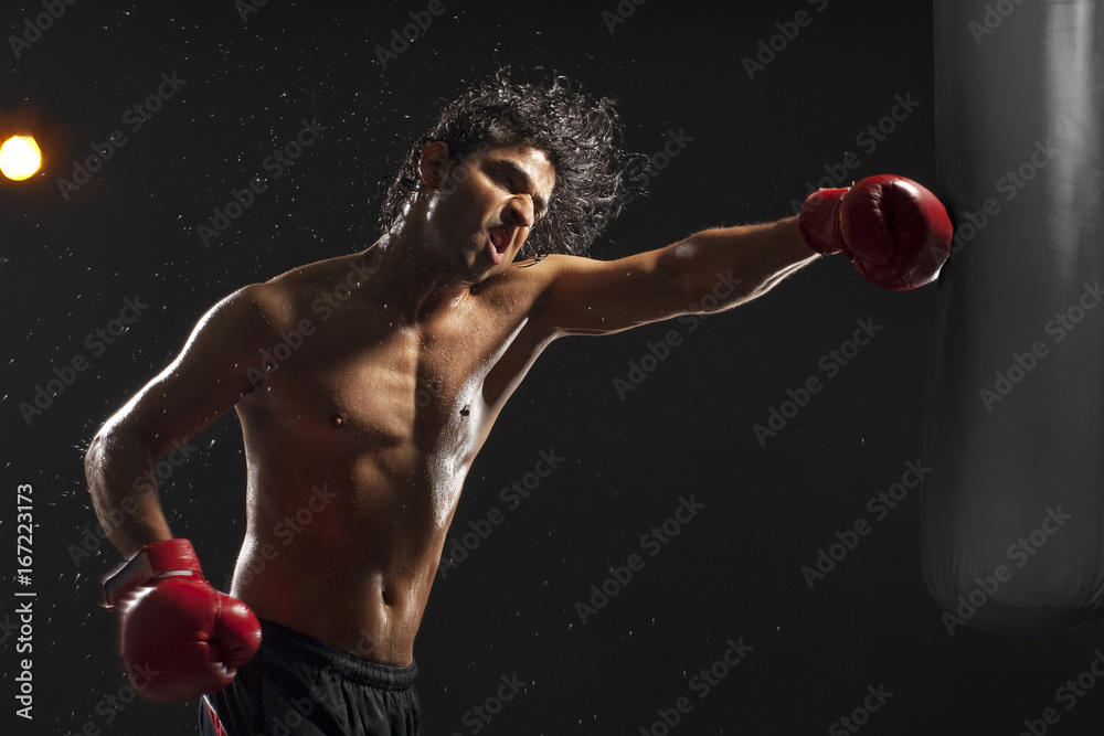 Boxer hitting punching bag over black background Boxer hitting punching bag over black background