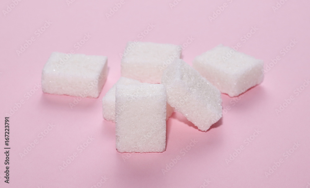 White sugar cubes isolated on pink background and texture