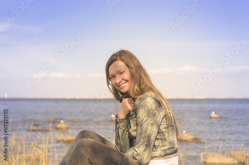 Attractive smiling blonde woman is sitting on the water background © Michael Kachalov