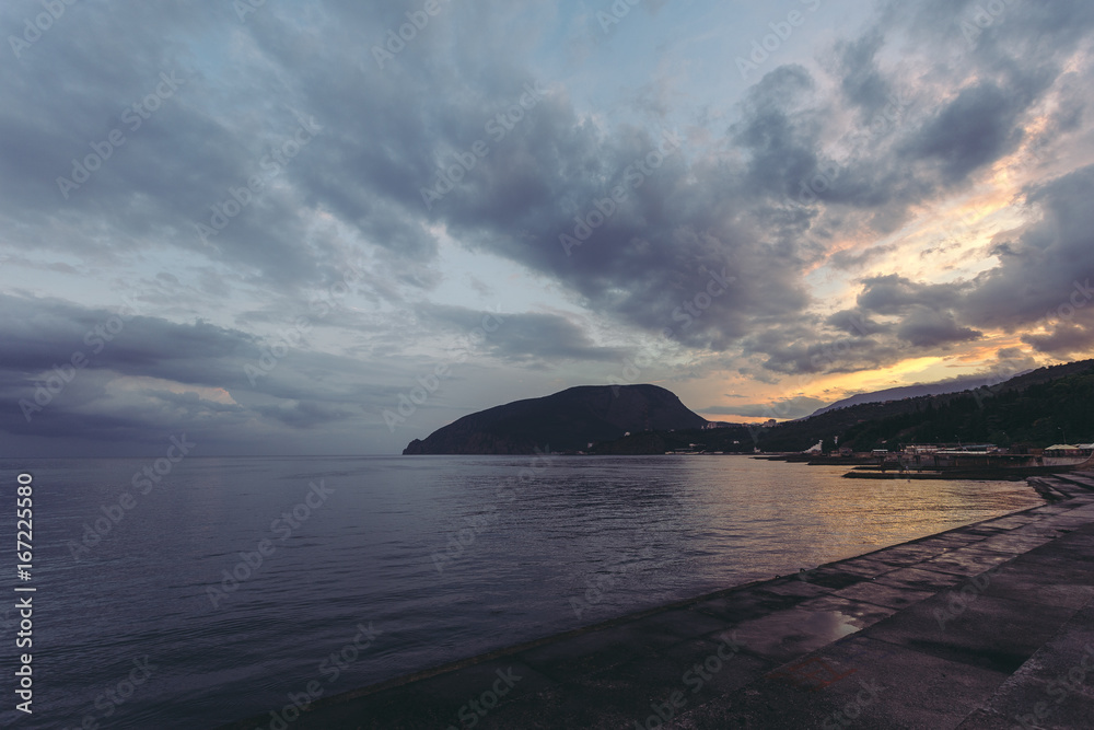 Sea. Mountains and the sea. Landscape background. Quaint clouds over the sea. Incredible sunset. Partly cloudy. Crimea. Summer. Evening scenery. Card with beautiful views.