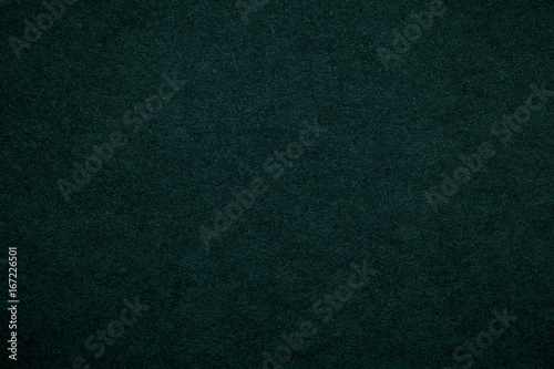 Texture of old dark green paper background, closeup. Structure of dense emerald cardboard