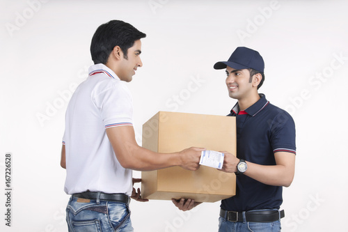 Delivery man giving package to customer against white background © IndiaPix
