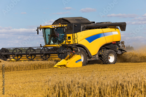 Yellow combine harvester on a wheat field with blue sky © Rob Rye