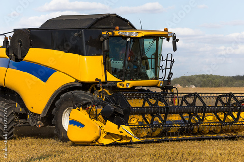 Yellow combine harvester on a wheat field with blue sky